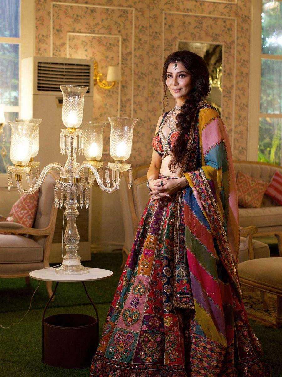 Dr. Jai Madaan, styled by Tanya Jain in a multicoloured lehenga in a room lit by candelabra