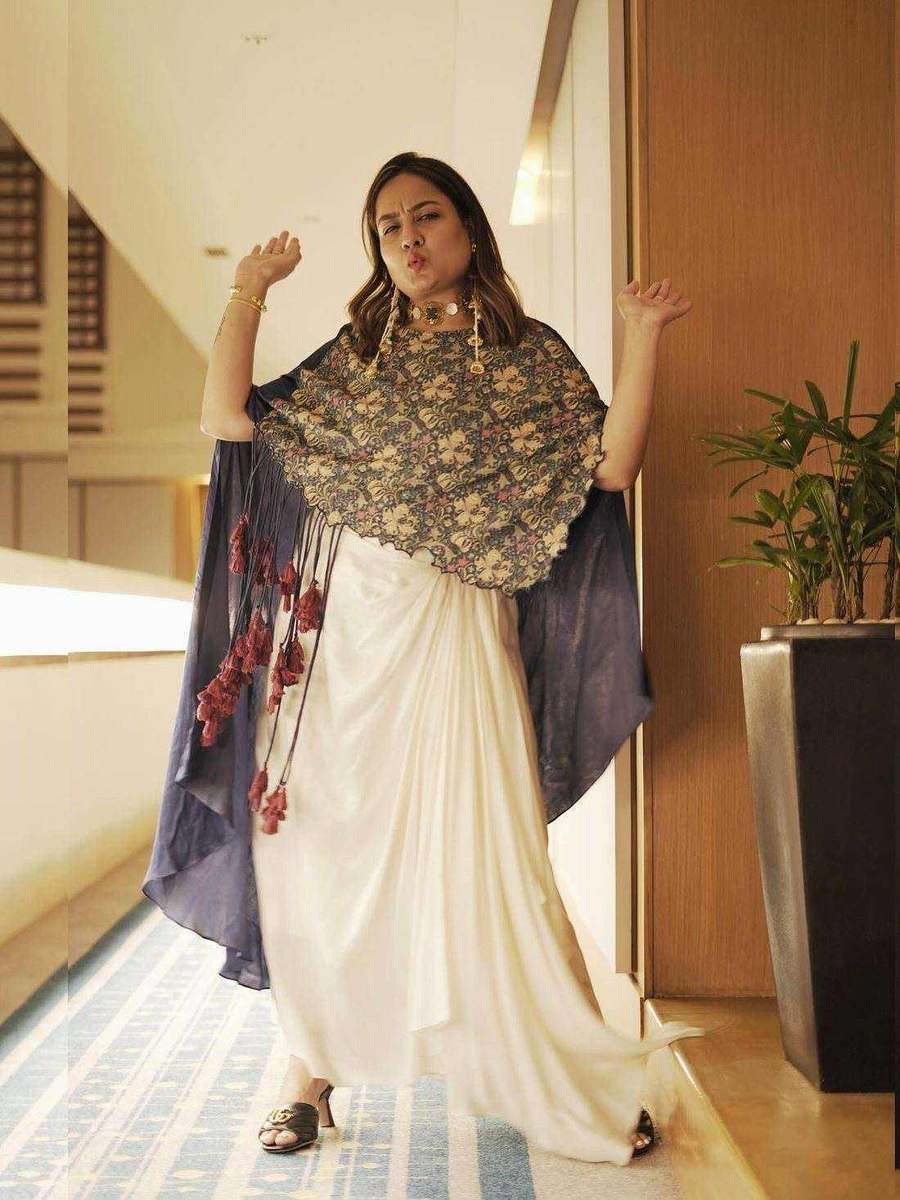 A styling client of Tanya Jain in an ivory drape gown with an embellished cape, standing in a hotel interior