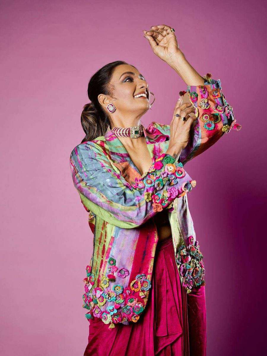 Shanthi Priya, styled by Tanya Jain in a magenta drape and embroidered jacket, arms raised against a pink backdrop